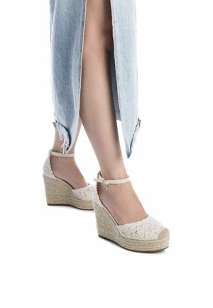 Zapatos de cuña blancos con parte superior de encaje texturizado y suelas envueltas en yute, que cuentan con una correa para el tobillo y un diseño de punta abierta.