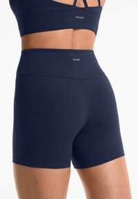 Marinblå högmidjade träningsshorts i mjukt stretchmaterial. Har logodetalj vid midjan och en figursydd, strömlinjeformad silhuett.