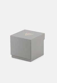 Cutie gri texturată cu un logo triunghiular auriu pe partea de sus. Cutia are un design cu clapetă deschisă, potrivită pentru ambalarea articolelor mici.