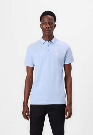 Svetlo modra polo majica iz mehke tkanine, z ovratnikom, dvema gumboma in kontrastnimi belimi detajli na rokavih. Preprost logotip na prsih.