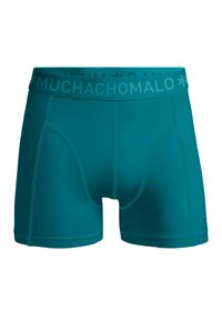 Turkizne bokserice, izdelane iz raztegljivega materiala, s širokim pasom z napisom "MUCHACHO" in šivanimi akcenti ob straneh.
