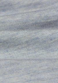 Světlomodrá pletená látka s jemnou texturou. Obsahuje různé odstíny modré a těsný vzor tkaní. Detailní pohled zvýrazňuje detaily stehů.