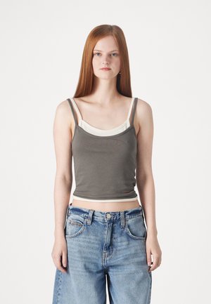 Gray cropped tank top layered over a white top, with thin straps. Worn with light blue high-waisted jeans featuring a classic five-pocket design.