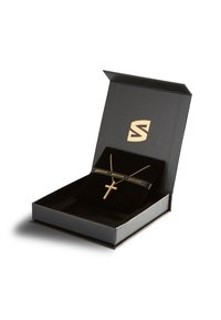Gold cross necklace displayed in a black box with a velvety interior. The box features a logo and the word "SERASAR" in gold lettering.