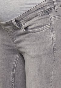 Jeans de mezclilla gris con un diseño ajustado, estilo de cinco bolsillos y un ligero desvanecimiento. La textura de la tela es suave y tiene un ligero estiramiento.