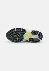 Running shoe outsole featuring a multi-textured design with black, green, and yellow accents, molded rubber for traction and durability.