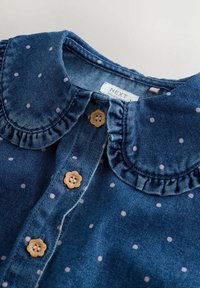 Denimhemd mit einem Rüschensaum, blauer Stoff, rosa Pünktchen und Blumenknöpfen. Etikett mit der Aufschrift "NEXT".