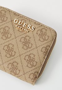 Smešasti novčanik od tkanine s reljefnim uzorkom logotipa i zlatnim natpisom "GUESS EST 1981". Zatvaranje na patentni zatvarač s teksturiranom površinom.