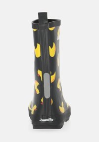 Black rubber rain boot featuring a pattern of yellow ducklings and a rear pull tab for easy wear. Smooth texture and flat sole.