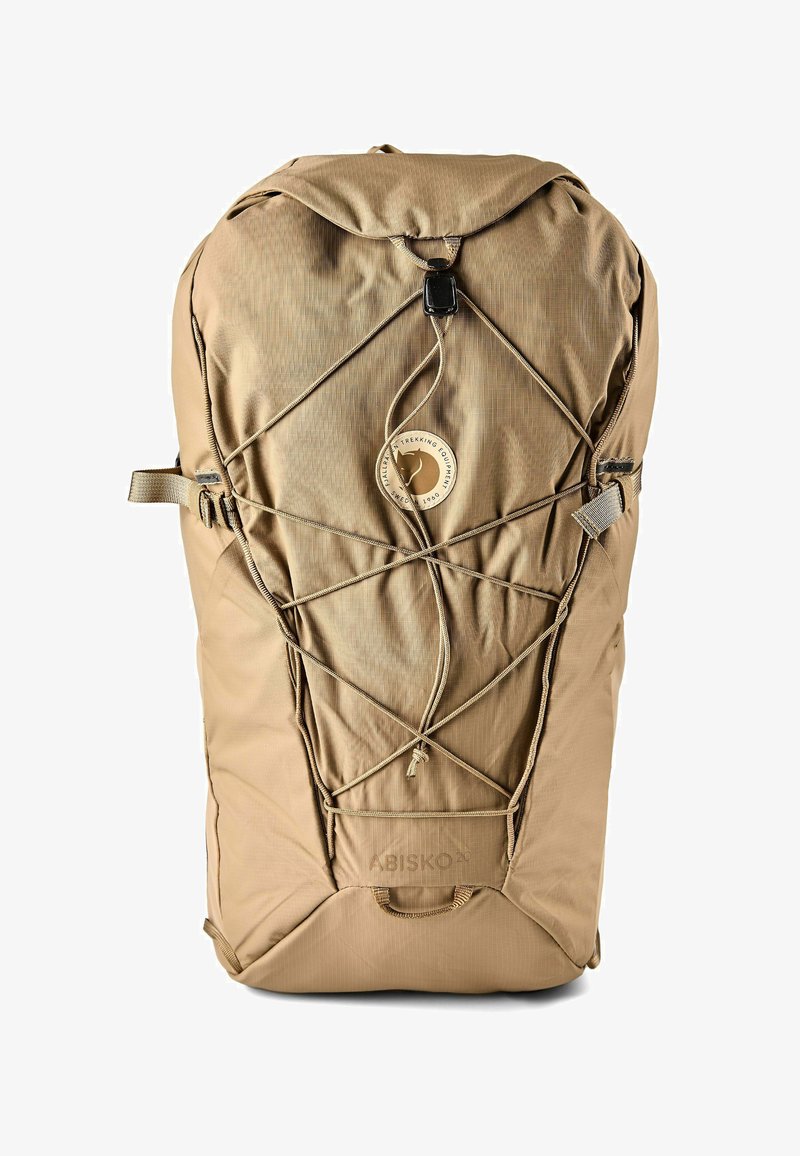 Sac à dos de randonnée couleur fauve avec cordons élastiques réglables à l'avant, sangles de compression latérales, et emblème rond avec logo de trekking au centre.