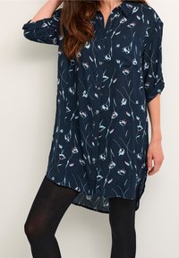 Navy-blaues Hemd mit Knopfverschluss und floralem Muster in Hellblau und Rot. Lange Ärmel, lockere Passform, geschwungener Saum, aus leichtem Material.