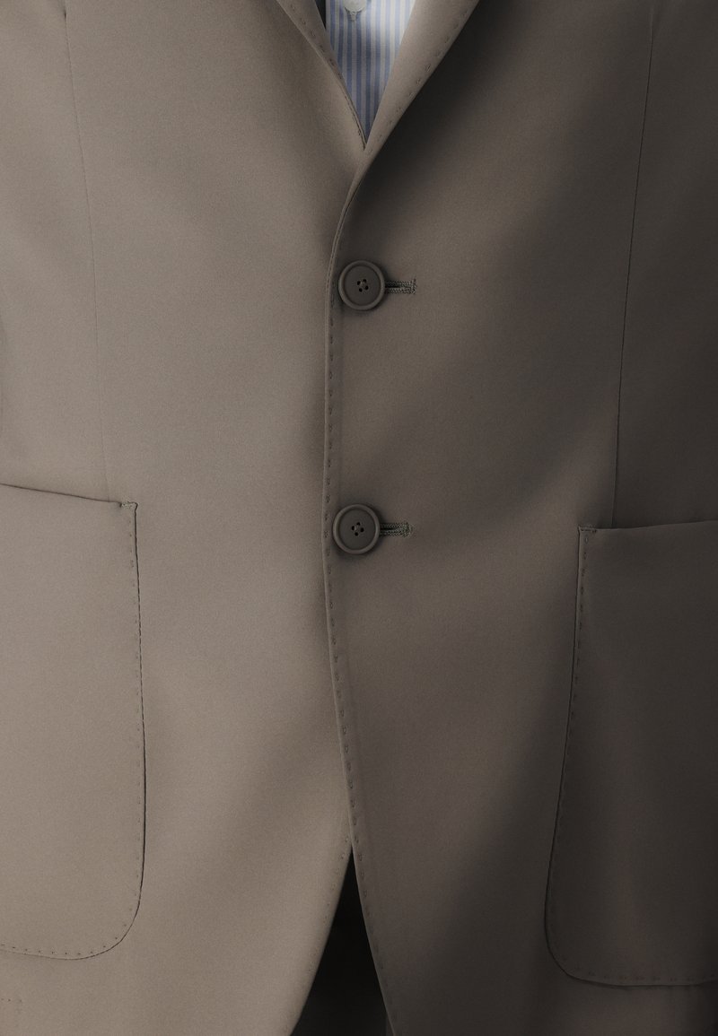 Veste de costume marron clair en tissu lisse, avec deux boutons, deux poches avant et un revers cranté.