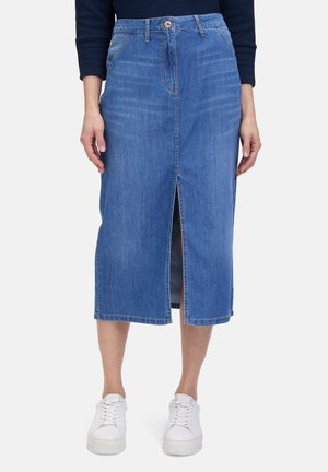 Denim-Midi-Rock mit einem vorderen Schlitz, hellblauer Farbe, klassischem Fünf-Taschen-Design und einer taillierten Taille. Kombiniert mit weißen Sneakers.