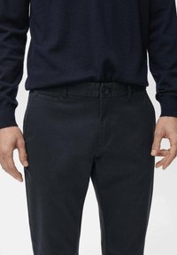 Dunkelblaue Baumwollhose mit glatter Textur, Knopfverschluss, frontalen Taschen und schlankem Schnitt.