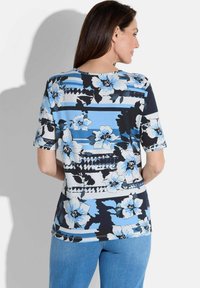 Blauwe bloemen top met korte mouwen, met een mix van strepen en patronen, voorzien van contrasterende zwarte accenten. Gemaakt van lichtgewicht stof.