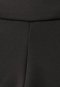 Czarne legginsy z teksturowanej tkaniny, z gładkim paskiem w talii i detalami szwów. Materiał jest elastyczny i przylegający do ciała.