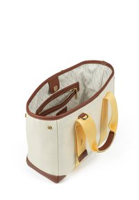 Sac en toile crème avec des accents en cuir marron et des poignées en tissu jaune. L'intérieur comprend une poche zippée et un revêtement doux.