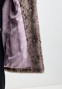 Szürke műszőrme kabát fényes, világoslila selyem béléssel, texturált külső résszel és sima szegéllyel. A szőrme részlet jól látható a széleken.