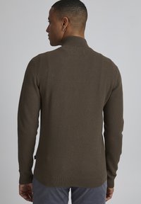 Brown textured sweater with a high collar and ribbed cuffs, featuring a slim fit and a subtle weave pattern. Back view shown.