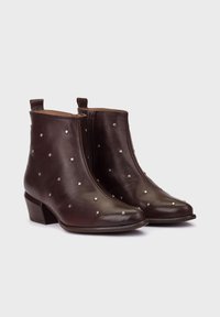 Bruine leren enkellaarsjes met zilveren studs, ritssluiting en een lage blokhak. Kenmerkt zich door een gladde textuur en een ronde neus.
