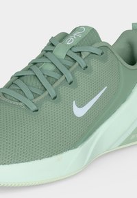 Baskets Nike vert clair avec dessus en mesh, lacets, logo swoosh blanc et une épaisse semelle blanche inclinée montrant le côté et le dessus.
