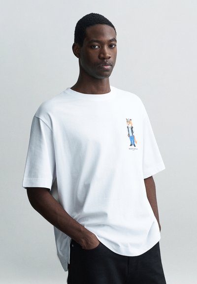 White cotton t-shirt featuring a cartoon character design on the left chest. The shirt has a relaxed fit and short sleeves.