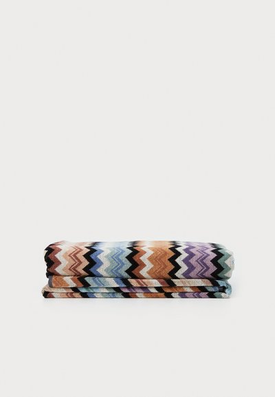 Set di asciugamani in cotone multicolori piegati, con un motivo a zigzag nei toni di arancione, blu, viola e nero su una superficie texturizzata.