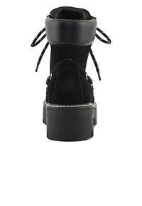 Botín negro de ante hasta el tobillo con un cuello alto y acolchado, cordones planos y suela de goma gruesa. Presenta detalles en hardware dorado y costuras reforzadas.