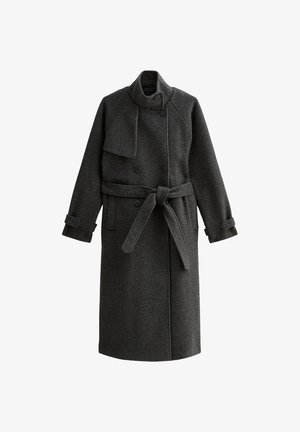 Donkergrijze wollen jas met een hoge kraag, dubbele knoopsluiting, strikband in de taille en knoopmanchetten. Soepele textuur, knielang.