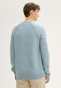 Hellblaues Strickpullover mit strukturiertem Muster, Raglanärmel und gerippten Bündchen und Saum. Mit Rundhalsausschnitt und lockerer Passform.
