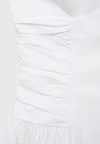 Witte jurk met geplooide textuur op het lijfje, gladde stof en geraffineerde accenten in de taille. Eenvoudige halslijn en vloeiende rok.