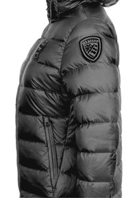 Schwarze Steppjacke mit einem seitlichen Reißverschlusstaschen, gesteppter Textur und einem markanten Schild-Logo auf der Schulter.