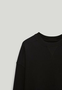 Felpa nera con scollo rotondo e maniche raglan, realizzata in un tessuto liscio con dettagli di cucitura minimi.