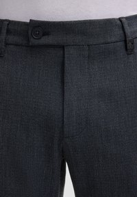 Dunkelgraue Hose aus strukturiertem Stoff, figurbetonter Schnitt, Knopfverschluss und eine sichtbare Tasche in der Nähe des Bunds.