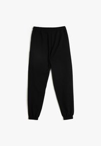 Schwarze Jogginghosen aus weichem Stoff, mit einem elastischen Bund und eng zulaufenden Säumen, mit glatter Textur und ohne sichtbare Muster.