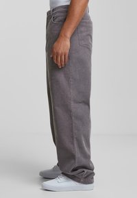 Grijze corduroy broek met een rechte pijpdesign, voorzien van een gestructureerd ribbeloppervlak, zijzakken en een achterzak. Gemaakt met witte schoenen.