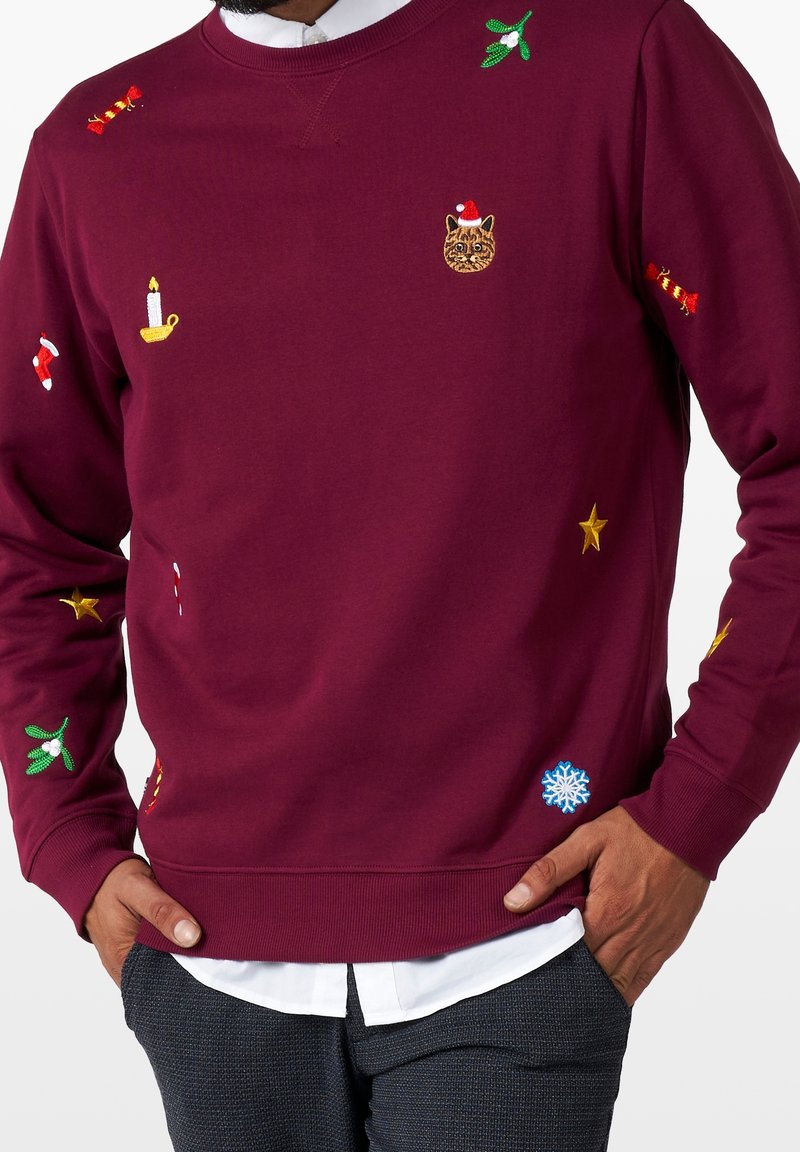 Borgå sweatshirt med olika färgglada broderier i helgtema, inklusive en katt, stjärnor, misteltein, ljus och snöflingor.