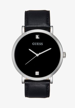 Montre avec bracelet en cuir noir, boîtier rond en acier argenté, cadran noir, aiguilles blanches et un accent carré à 12 heures. Présente un design minimaliste.