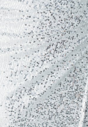 White fabric with a textured surface, densely covered in silver and black sequins, creating a shimmering effect with a smooth finish.