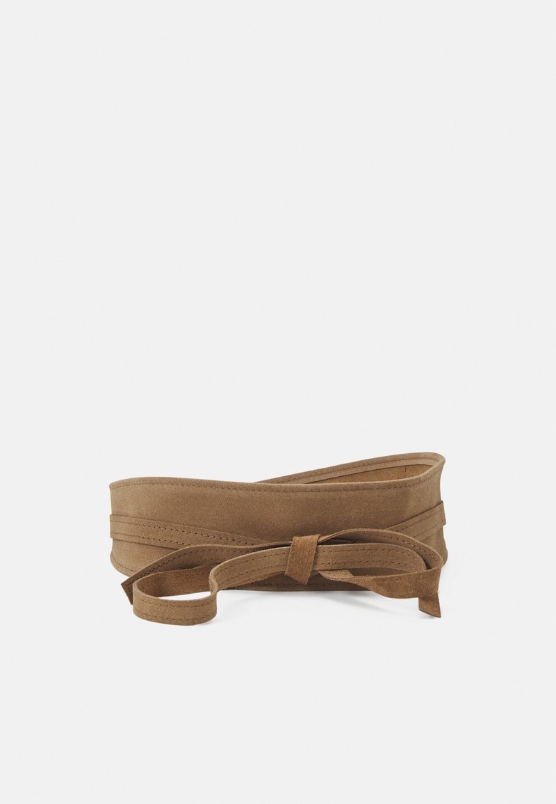 Large ceinture en daim marron avec une longue lanière nouée en un nœud lâche sur un fond blanc uni.