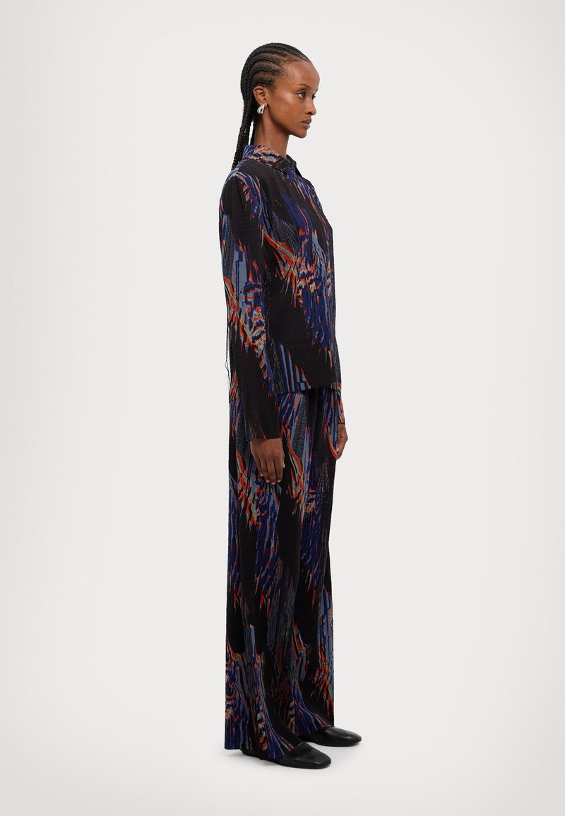 Fekete hosszú ujjú ruha, kék és vörös színű színes absztrakt mintával. Sima anyag, laza fazon, gallérral és bő nadrággal.