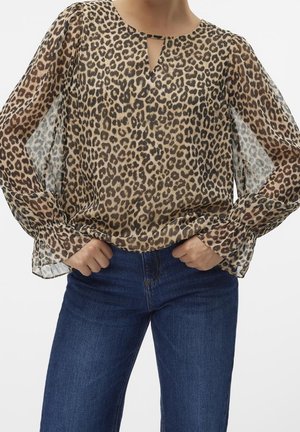 Blusa con stampa leopardata, maniche lunghe trasparenti, scollatura a forma di chiave e polsini elasticizzati. Realizzata in tessuto leggero e fluido. Abbinata a jeans blu.