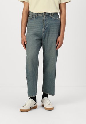 Jean en denim bleu clair avec une coupe droite, taille haute et un design minimaliste. Le tissu a une finition délavée et une texture subtile.