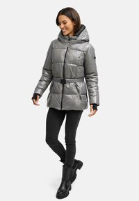 Graue, gepolsterte Jacke mit Kapuze, Reißverschluss, verstellbarem Gürtel und schwarzen Akzenten. Getragen mit schwarzen Jeans und klobigen schwarzen Stiefeln.