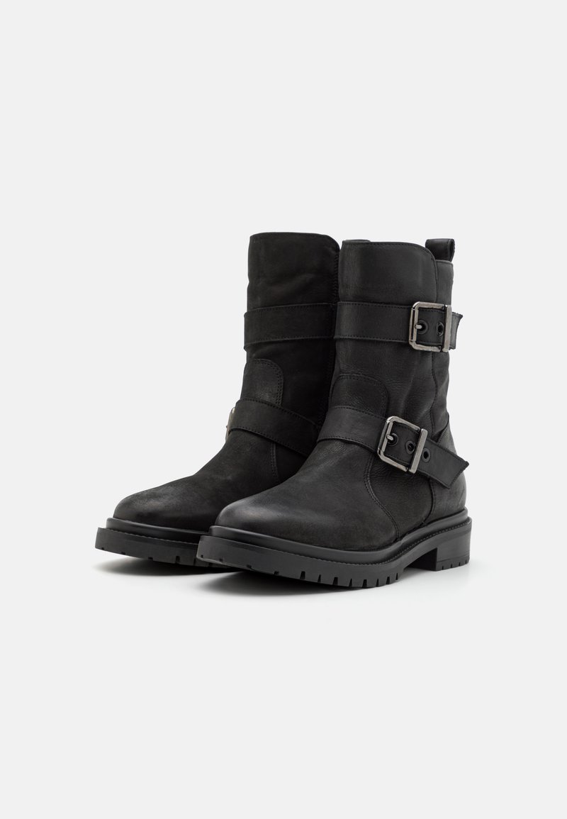 Schwarze Leder-Stiefeletten mit Schnallenriemen, strukturiertem Finish, verstärkter Zehenkappe und Gummisohle für Trittfestigkeit. Höhe: bis zur Mitte des Waden.