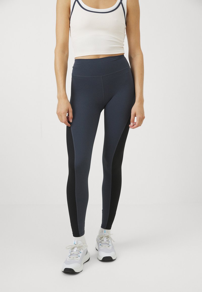 Høyt livde navy tights med svarte sidedele, laget av stretch-stoff, med en glatt tekstur og uten synlige detaljer.