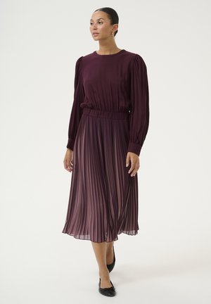 Plum-colored pleated midi dress with long puff sleeves, a fitted waist, and a smooth texture, paired with black flats.