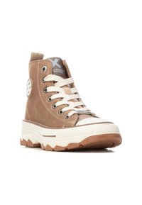Sneaker alte marrone chiaro con finitura scamosciata, lacci bianchi, suola in gomma e un logo circolare sul lato. Suola intermedia testurizzata e punta arrotondata.