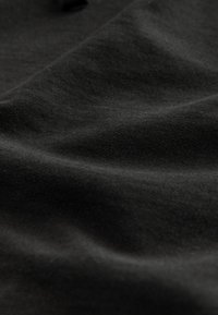 Material negru din bumbac cu o textură netedă, prezentând cute și pliuri subtile, indicând falduri și moliciune.