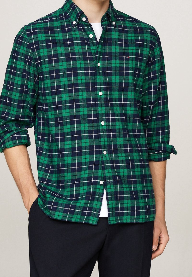 Camicia a quadri verde e blu navy in cotone, con colletto abbottonato e bottoni bianchi, maniche arrotolate e vestibilità rilassata.